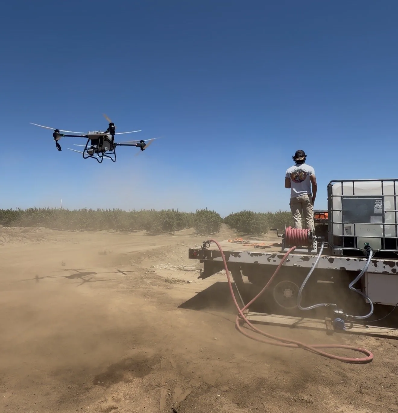 Agricultural drone in flight beside a field operations truck in a Southern California orchard
